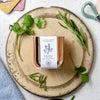 Rosemary & Coriander in a copper tin, sitting on top of a chopping board with some cut herbs.