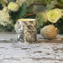  Affirmation candle in a Bone China container printed with a hand-drawn illustration of the plants used in the fragrance, including oud, jasmine, and nutmeg. Around the rim is a stripe of shiny 24k gold.