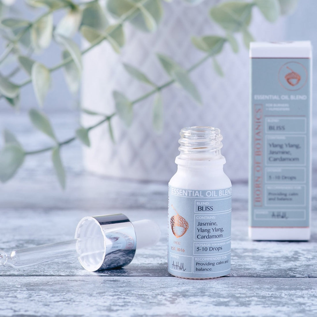  A small white bottle with a baby blue label sits against a pale grey background. The pipette-lid is removed and lies next to it.