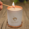 The Sleep candle sits on a wooden table, and is being lit with a match.