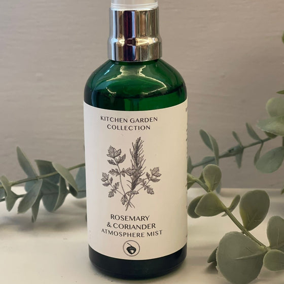 A green glass spray bottle with a white label featuring a hand-drawn design of a bundle of herbs.